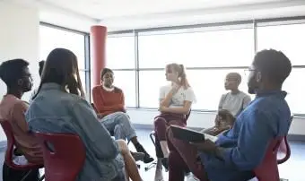 グループミーティングでメンタルヘルスインストラクターと座りながらシェアする女性