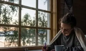 日記を書く窓際に座っている女性