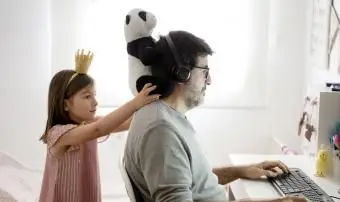 Uomo che fa il telelavoro e una bambina che gioca in giro