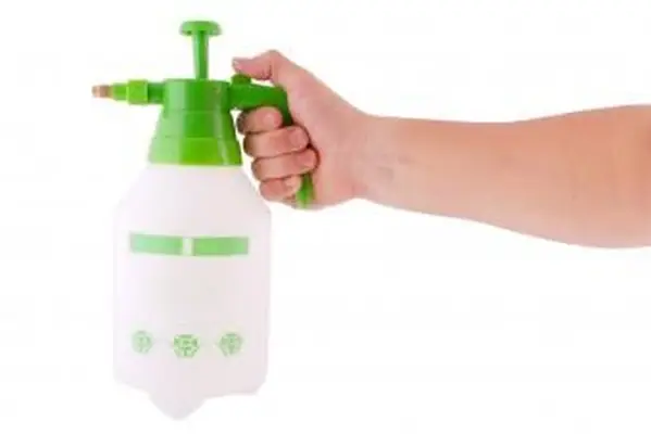 Botella de rociador a presión en la mano