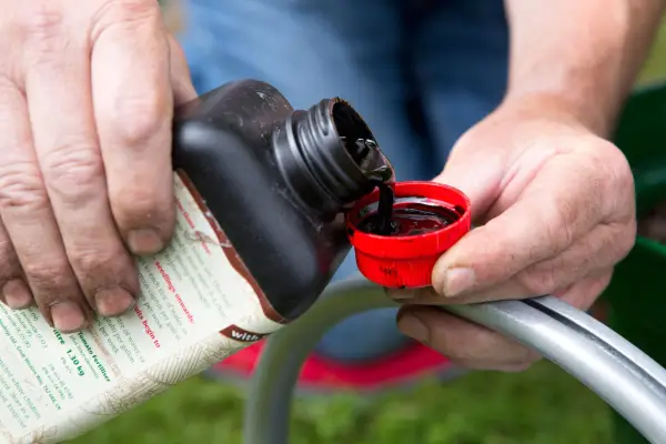Measuring a capful of liquid plant feed to dilute in a watering can of water
