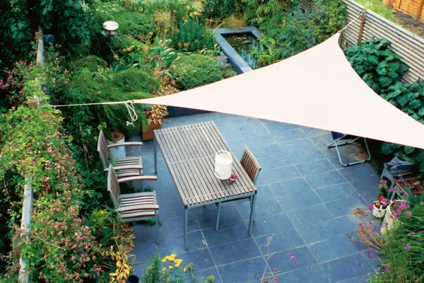 A shade sail over a patio seating area