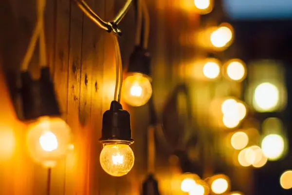 Strings of outdoor lights hanging along a garden fence (Photo credit: Getty)