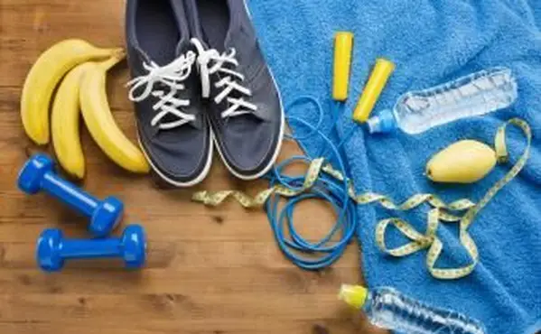 Concepto de fitness con zapatillas de deporte pesas saltando cuerda cinta métrica toalla botella de agua pera y plátanos