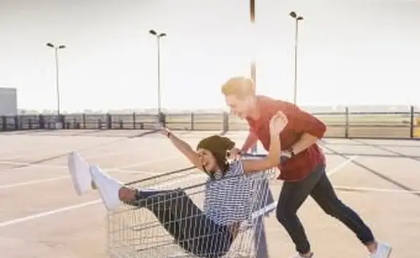 駐車場レベルでショッピングカートと遊び心のある若いカップル