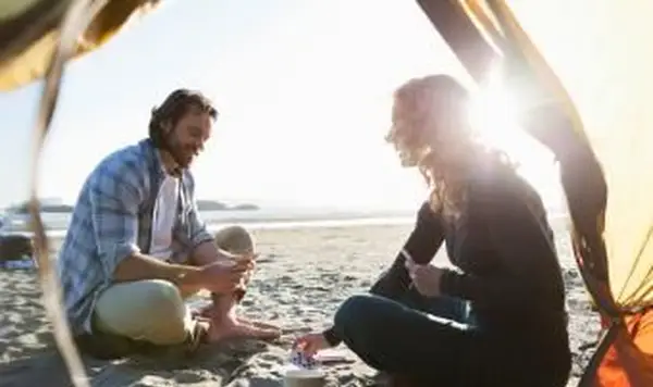 해질녘 해변에서 커플 캠핑 카드 놀이