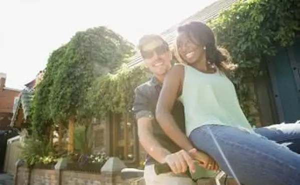 日当たりの良い歩道で自転車に乗る遊び心のあるカップル