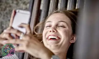 Mulher rindo enquanto usa um smartphone para enviar mensagens de texto