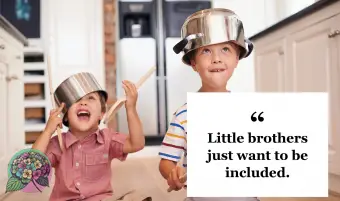 Deux jeunes garçons assis sur le sol de la cuisine jouant avec des casseroles et des poêles