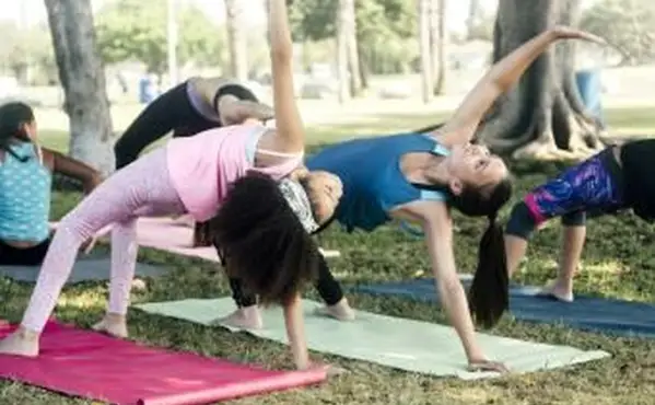 תלמידות בית ספר שמתרגלות יוגה מציבות במגרש המשחק בבית הספר
