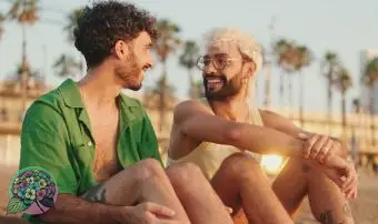 ビーチに座りながら話したり笑ったりするカップル