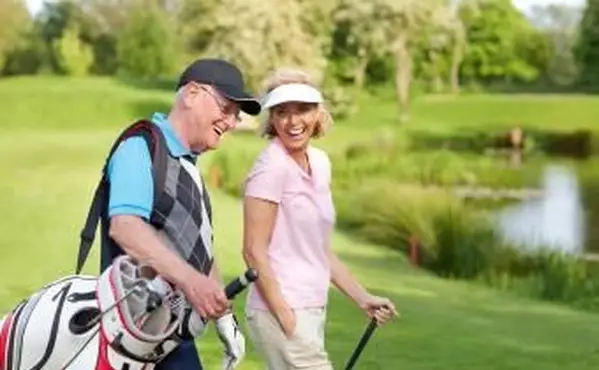 Couples mûrs gais marchant sur un terrain de golf