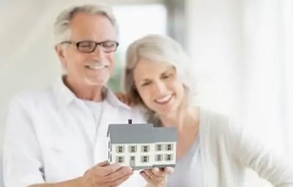 Starší pár drží v rukách modelku domov