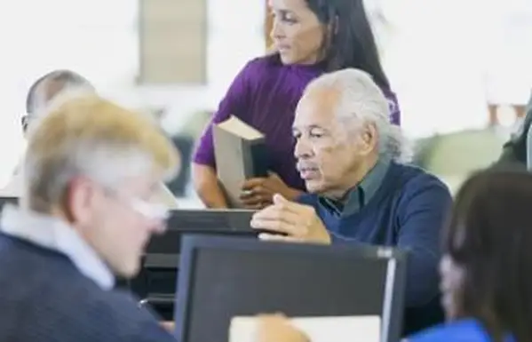 図書館のコンピューターで作業している高齢者のグループ