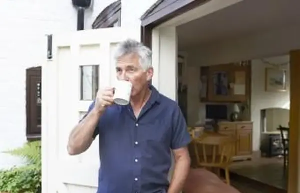 Homme mûr buvant du thé à la porte de sa maison