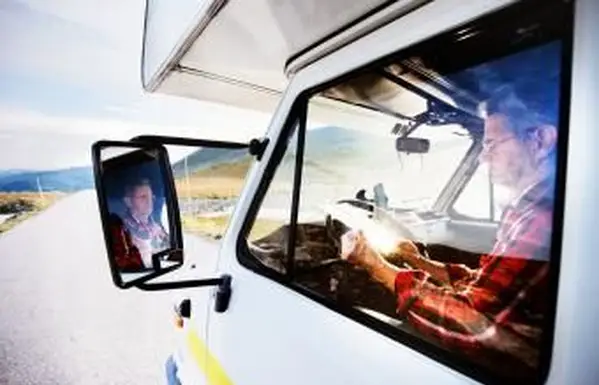 Senior uomo in camper guardando la mappa su strada in montagna