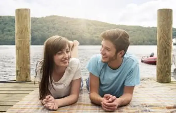 Młoda para leży na kocu nad jeziorem