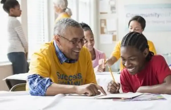 Wolontariusze udzielający korepetycji uczniom w klasie