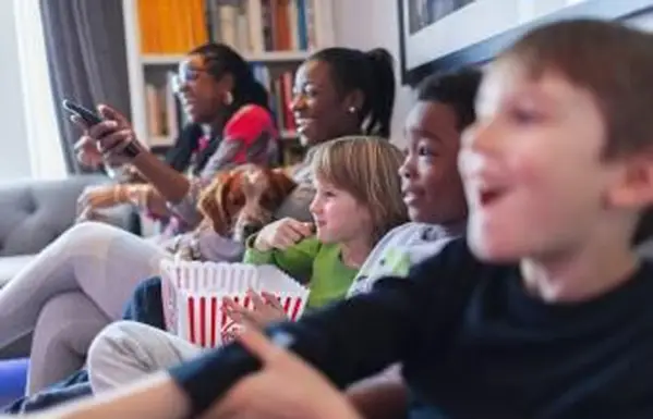 Wieloetniczna rodzina oglądająca filmy i jedząca popcorn