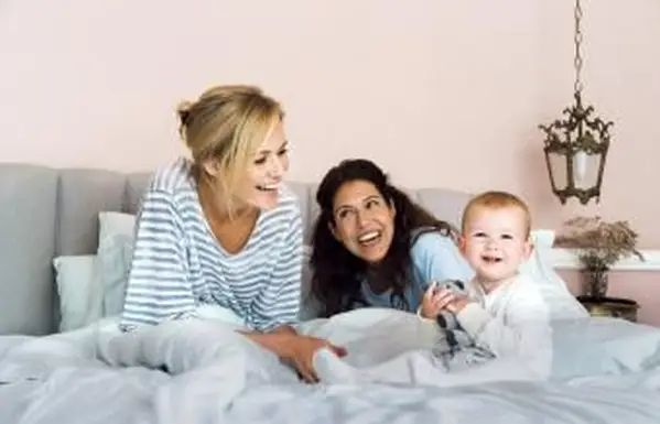 Pareja alegre con Baby Boy en la cama en casa