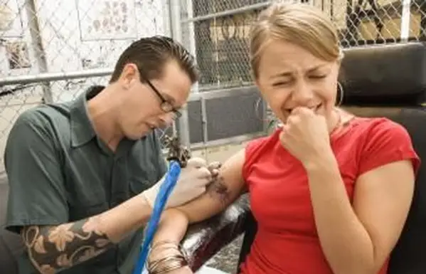 femme souffrant d'une douleur de tatouage inhabituellement élevée