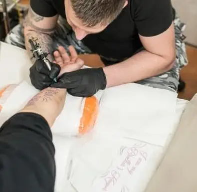 Tätowierer tätowiert Mann