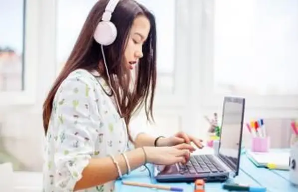 Teenager pomocou notebooku so slúchadlami na ušiach