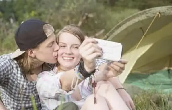 Młoda para całuje się i robi selfie za pomocą smartfona