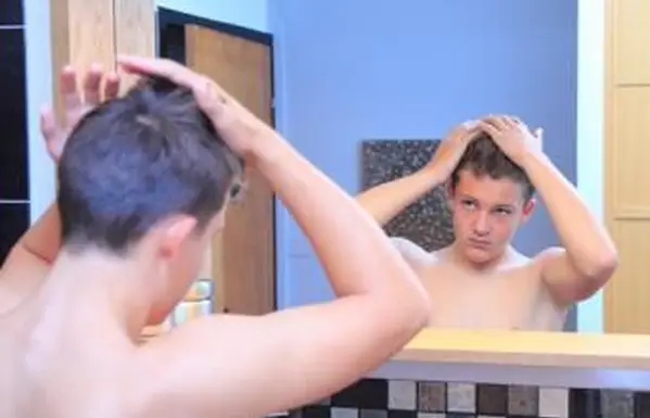 鏡で髪を修正する十代の少年