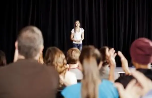 Audiencia aplaudiendo a una adolescente en el escenario