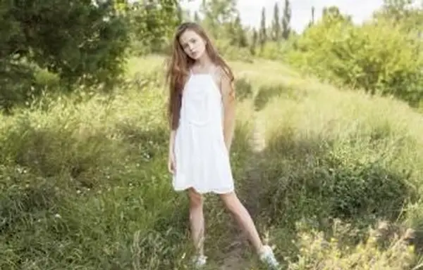 Menina em um campo de grama com um vestido branco de verão