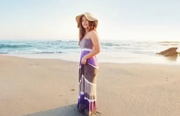 Menina adolescente com chapéu de palha e vestido maxi na praia