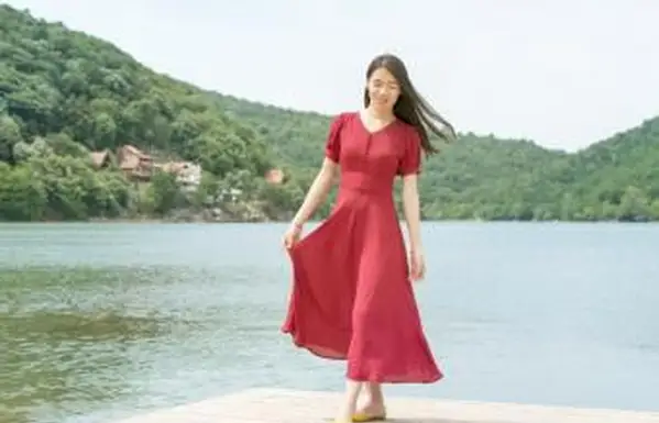 Menina em frente a um lago com um vestido longo vermelho