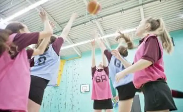 Studenti che saltano e giocano a basket durante la lezione di ginnastica