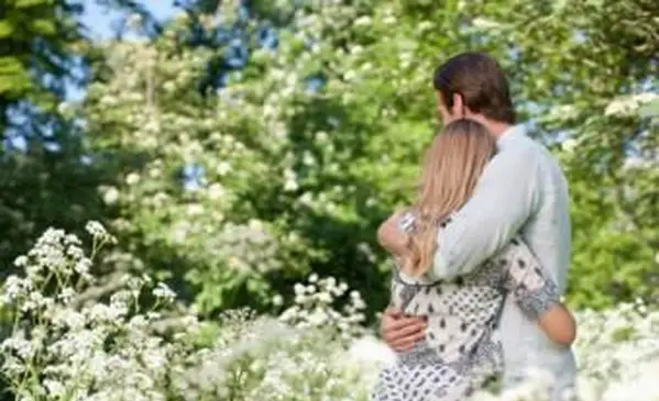 Para przytulająca się w polu kwiatów