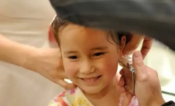 Menina fazendo piercing nas orelhas