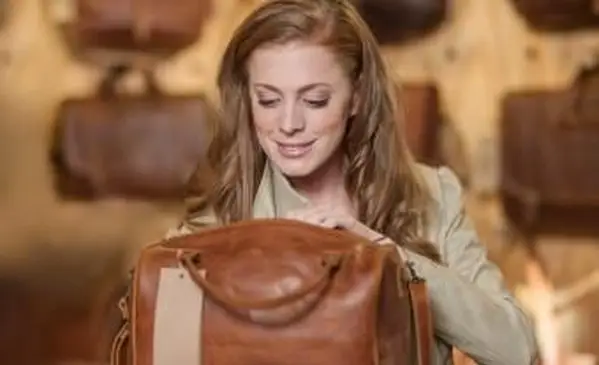 Mulher na loja olhando para uma bolsa de couro