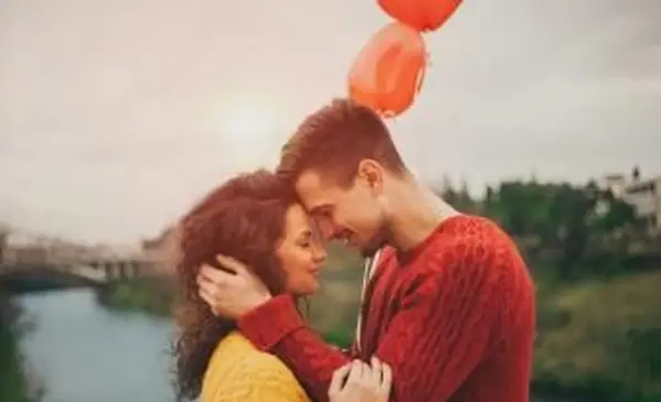 Junges Paar feiert Liebe und hält herzförmige Ballons