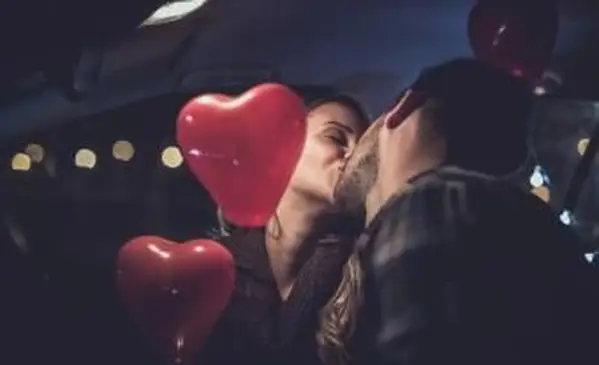 バレンタインで飾られた車の中でキスするカップル