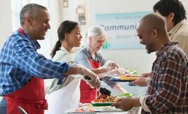 Dobrovoľníci podávajúci jedlo v komunitnej kuchyni
