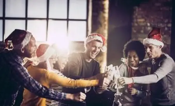 Radostný tím sa baví pri otváraní šampanského počas vianočnej oslavy