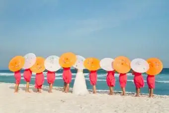 Nevesta so svojou družičkou držiac na pláži slnečníky