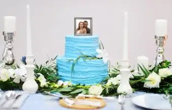 青い背景の上に赤いバラとレズビアンのカップルとピンクのウエディングケーキ