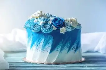 クリーム色の白い花で飾られた美しい青いウエディングケーキ