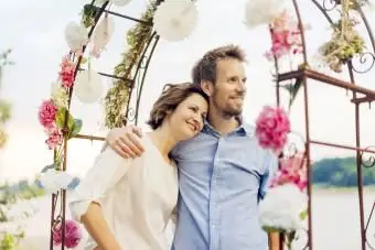 Coppia felice che si abbraccia sotto l'arco nuziale