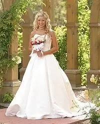 Panna młoda pozuje na zewnątrz w sukni ślubnej w stylu księżniczki