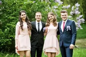 Demoiselles d'honneur en robes roses posant avec de beaux garçons d'honneur