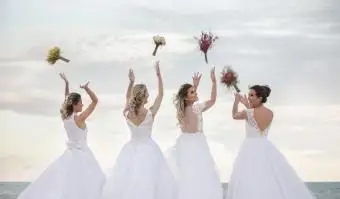 Novias lanzando ramos contra el cielo