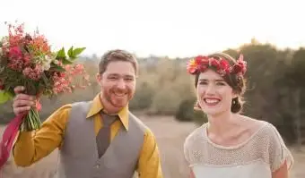 חתן וכלה מחייכים בשדה הכפרי