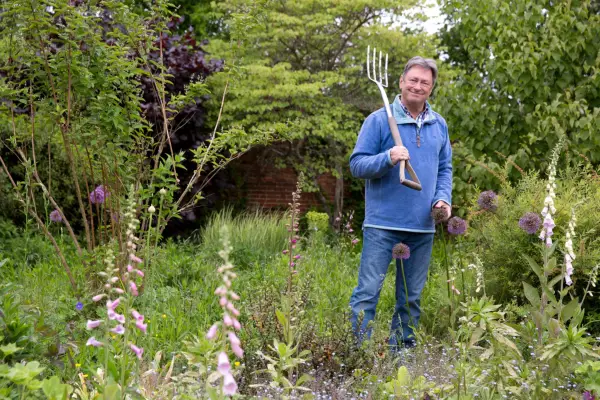 Alan Titchmarsh in his garden surrounded by plants including foxgloves and alliums